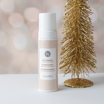 3-in-1 Sunless Tanning + Sculpting Foam next to a gold Christmas Tree